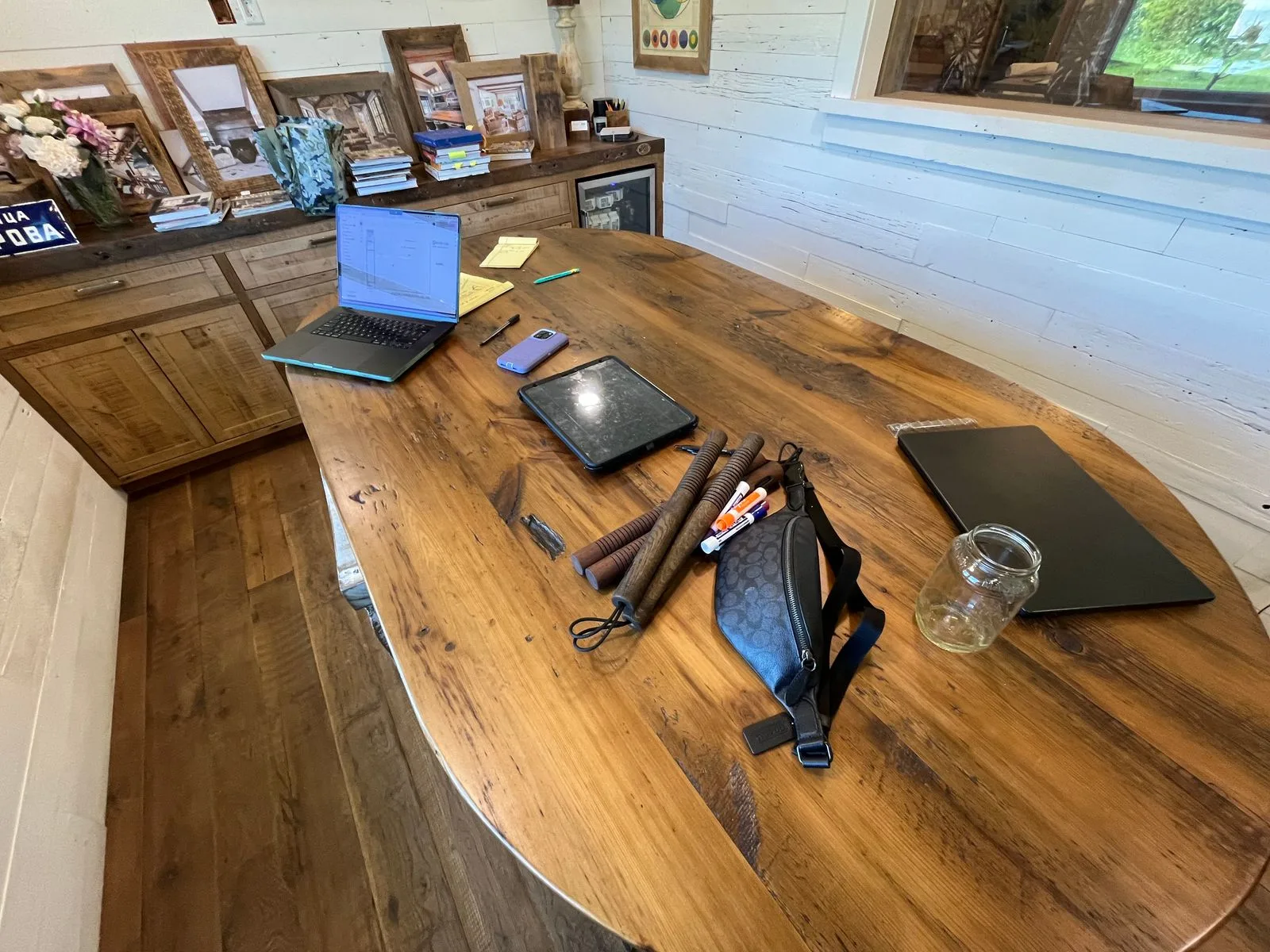 An oversized white oak nunchaku pair and a walnut pair on a reclaimed wood conference table during a work meeting at Heritage Beam & Board